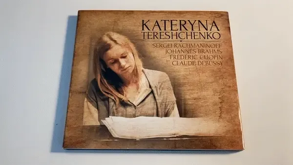 Animation of the printed CD in hand: the digipak is opened, booklet pages with musician photos are turned, the disc is shown in its tray, then the back with the track list